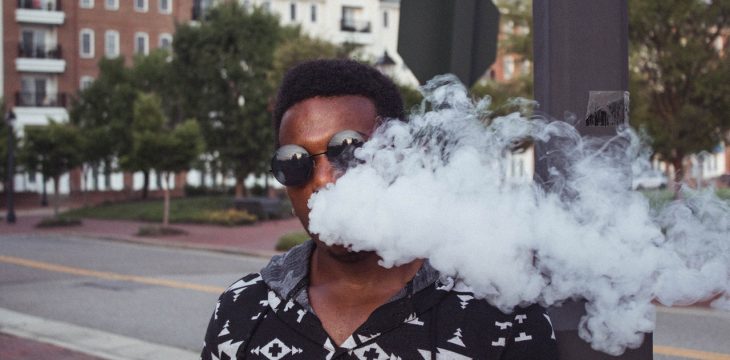 a man wearing glasses smoking on the street