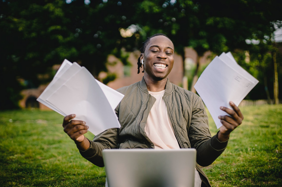 man holding papers with laptop in front of him